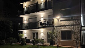 A multi-story building with balconies, outdoor seating, and a well-lit entrance. - Black Forest vacation apartment with dream terrace (Freudenstadt)