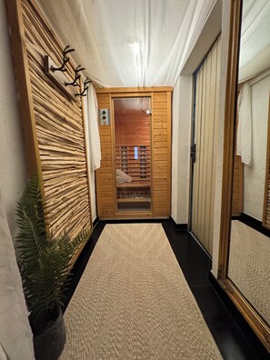 Un pasillo con pared de madera, una puerta de vidrio que da a una habitación y piso negro.