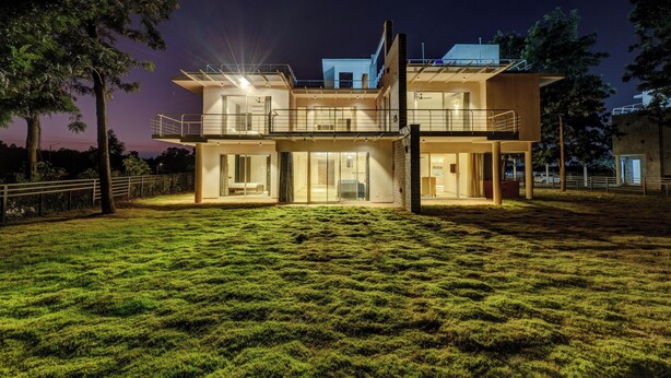 Un edificio moderno de dos pisos con techo plano, ventanas amplias y fachada bien iluminada.