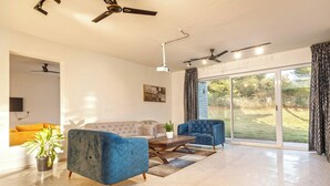 Una sala de estar moderna con un sofá, dos sillones, una mesa de centro y un ventilador de techo.