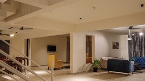 Un amplio espacio de sala con una escalera, un sofá, un televisor y una planta en maceta.
