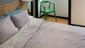Ein Schlafzimmer mit einem Bett, einem grünen Sessel, einem Fenster und einer Tür.