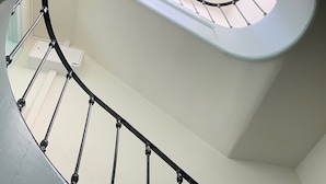 Eine geschwungene Treppe mit schwarzen Spindeln und einer weißen Wand.