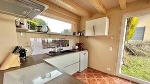 Una cocina compacta con encimera de madera, un fregadero, una cafetera y un refrigerador.