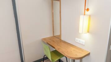 Een hoekbureau met een groene stoel, een houten plank erboven en een wandlamp.