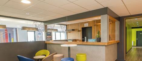 A modern interior with a reception desk, colorful stools, and a wooden floor.