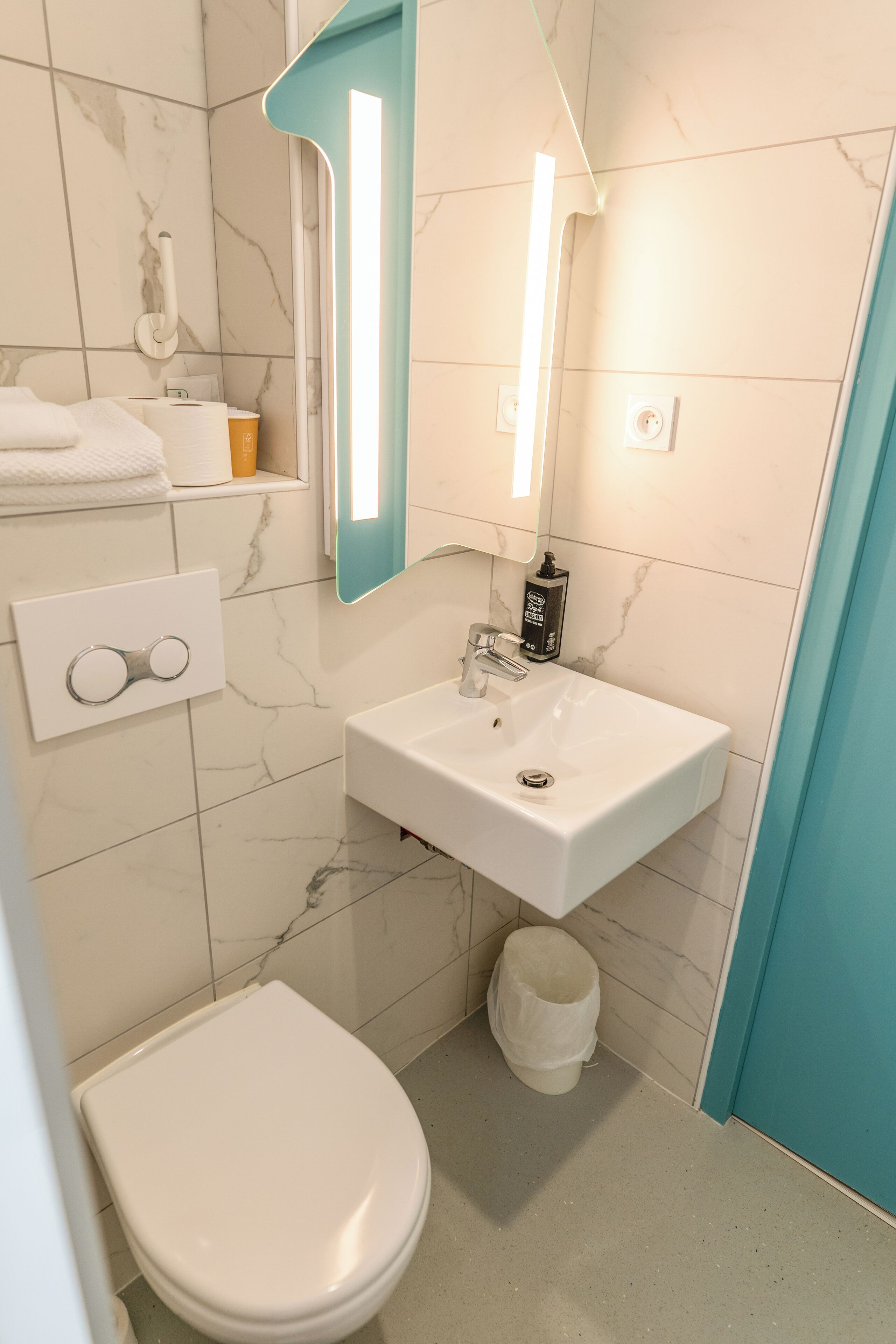 Une salle de bain avec des toilettes blanches, un lavabo avec un miroir au-dessus et un porte-serviettes avec des serviettes.