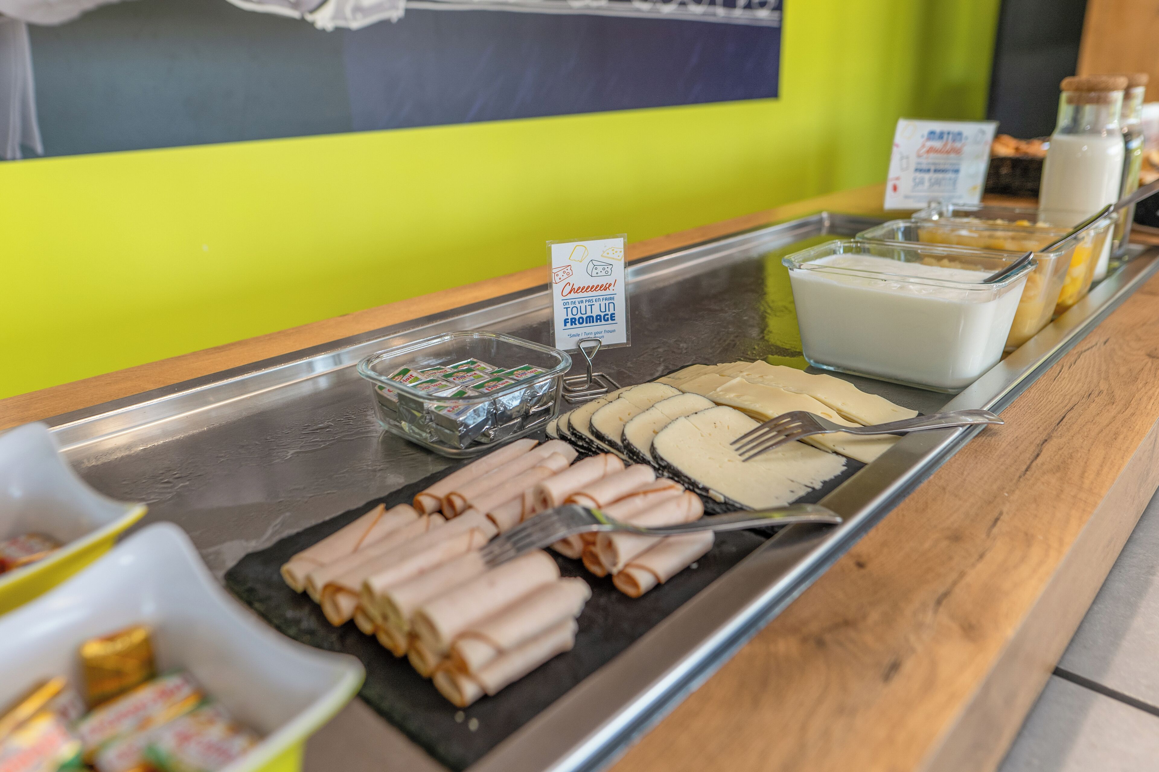 Un bufé con diversos alimentos, incluyendo carnes enrolladas, queso y yogur.