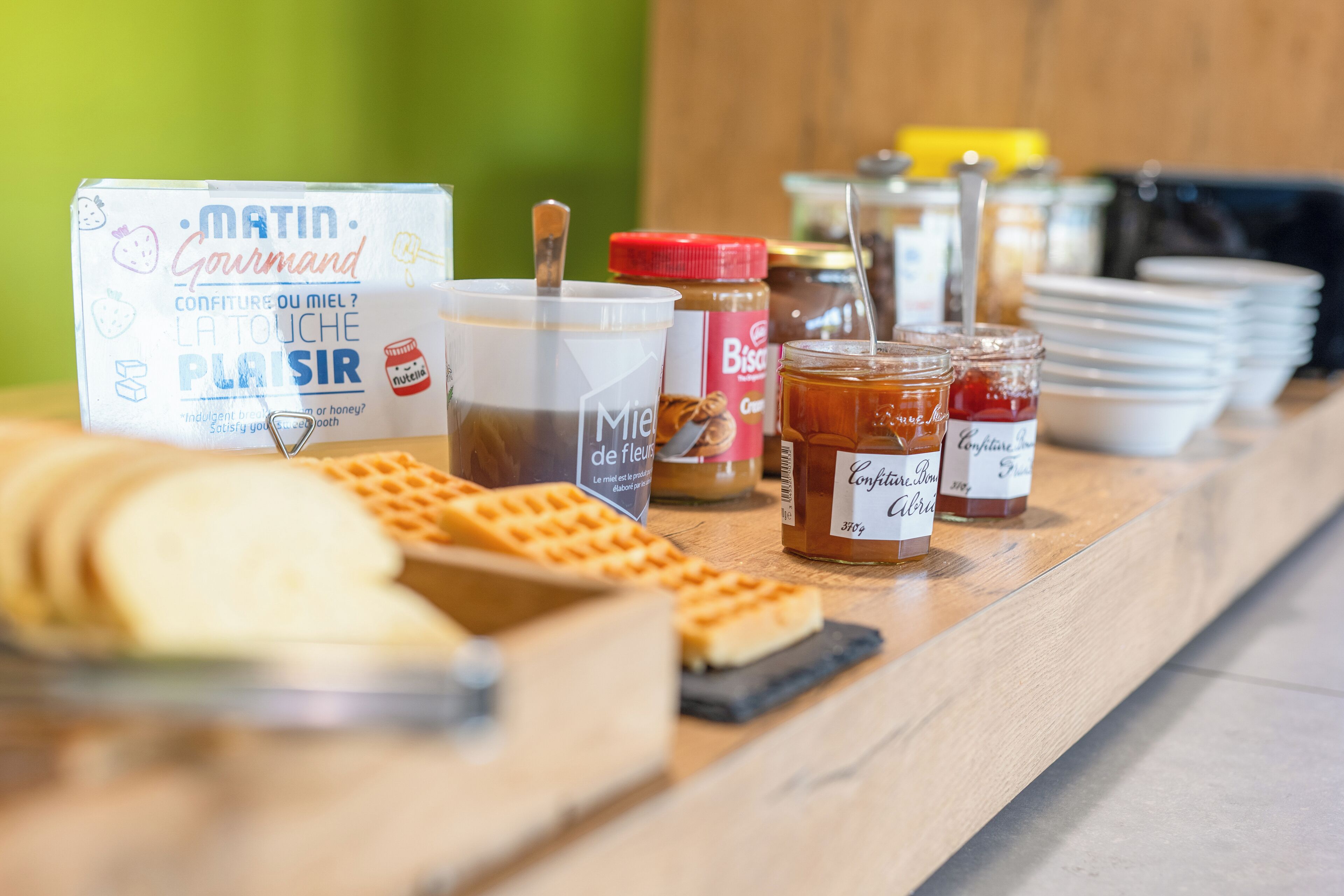 A breakfast buffet with waffles, jams, and honey.