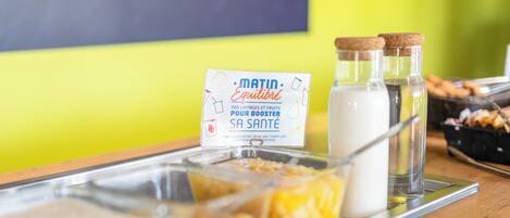 Un buffet per la colazione con diversi cibi e confezioni di latte su un vassoio.