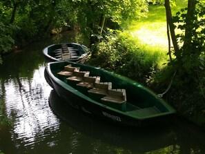 Ein grünes Boot liegt an einem ruhigen Fluss, umgeben von üppigem Grün.