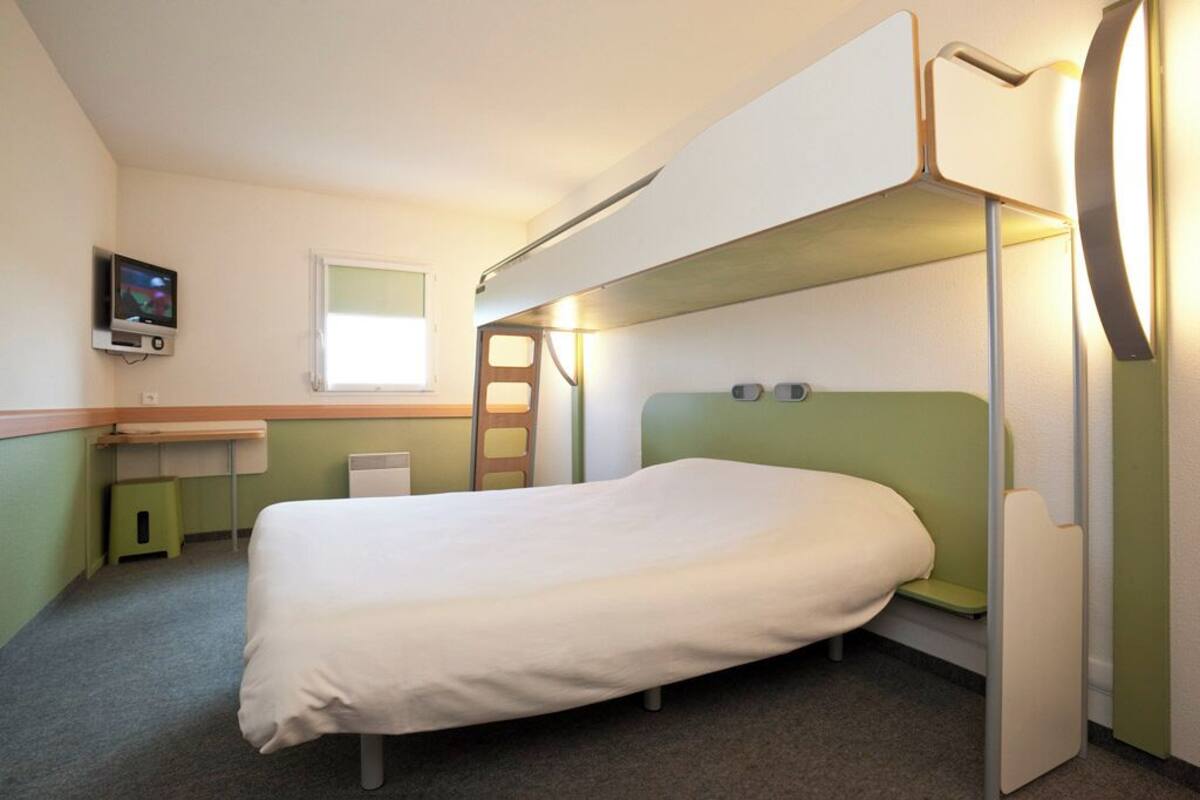 A bunk bed room with a desk and a television.