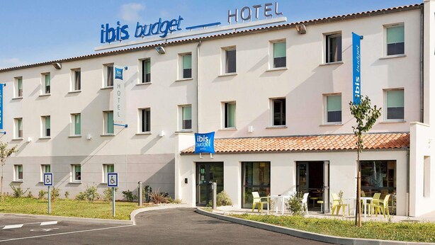 Een hotel met een bord waarop 'ibis budget HOTEL' staat en meerdere rolstoeltoegankelijkheidsborden.