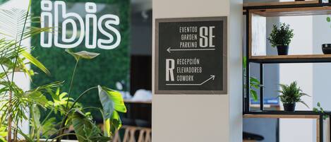 Señal con indicaciones hacia eventos, jardín, estacionamiento, recepción, ascensores y espacio de coworking.