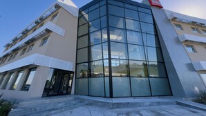 A modern building with a glass facade, a red logo on the corner, and a set of stairs leading to the entrance. - ibis Puerto General San Martin (Puerto General San Martín)