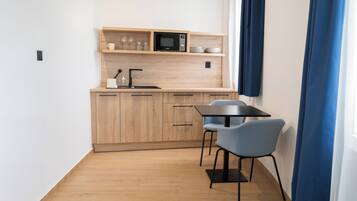 A modern kitchen with wooden cabinets, a black microwave, and a dining area with a table and chairs.