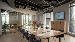 Une salle de conférence équipée d’une longue table, de chaises, d’un tableau blanc et d’un écran de télévision affichant le logo « ibis Styles ».