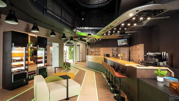 Un espace bar moderne doté d’un comptoir, de sièges et d’un distributeur automatique.
