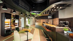 Un espace bar moderne doté d’un comptoir, de sièges et d’un distributeur automatique.