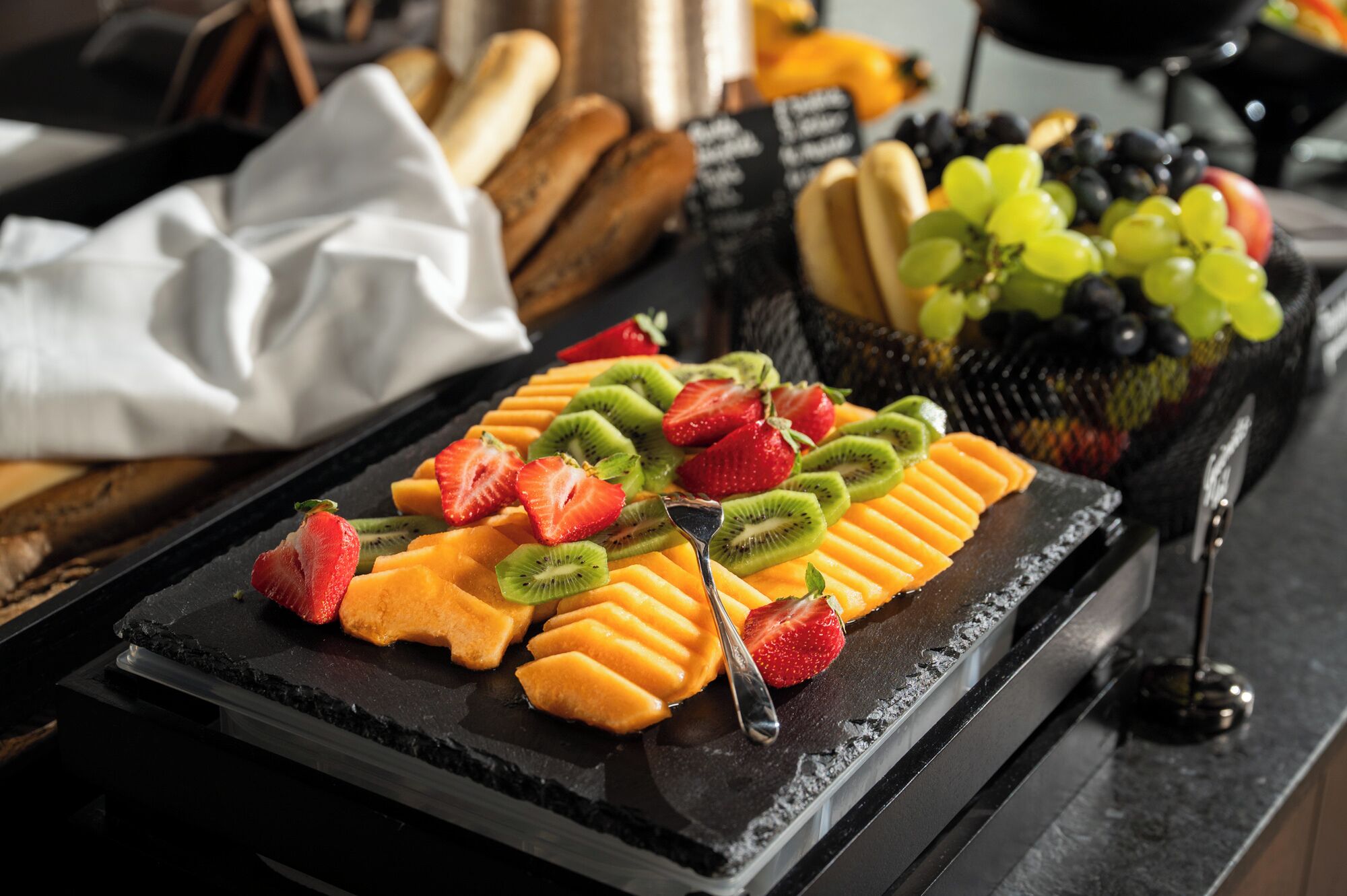 Un buffet de petit-déjeuner avec des fruits coupés et du pain.