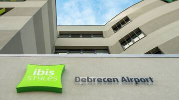 A building with a sign for 'Debrecen Airport' and a logo for 'ibis Styles'.