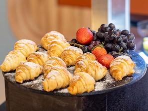 Variedad de pasteles y frutas frescas sobre una mesa de madera.