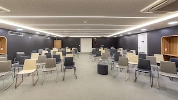 A conference room with rows of chairs, a podium, and a carpeted floor.