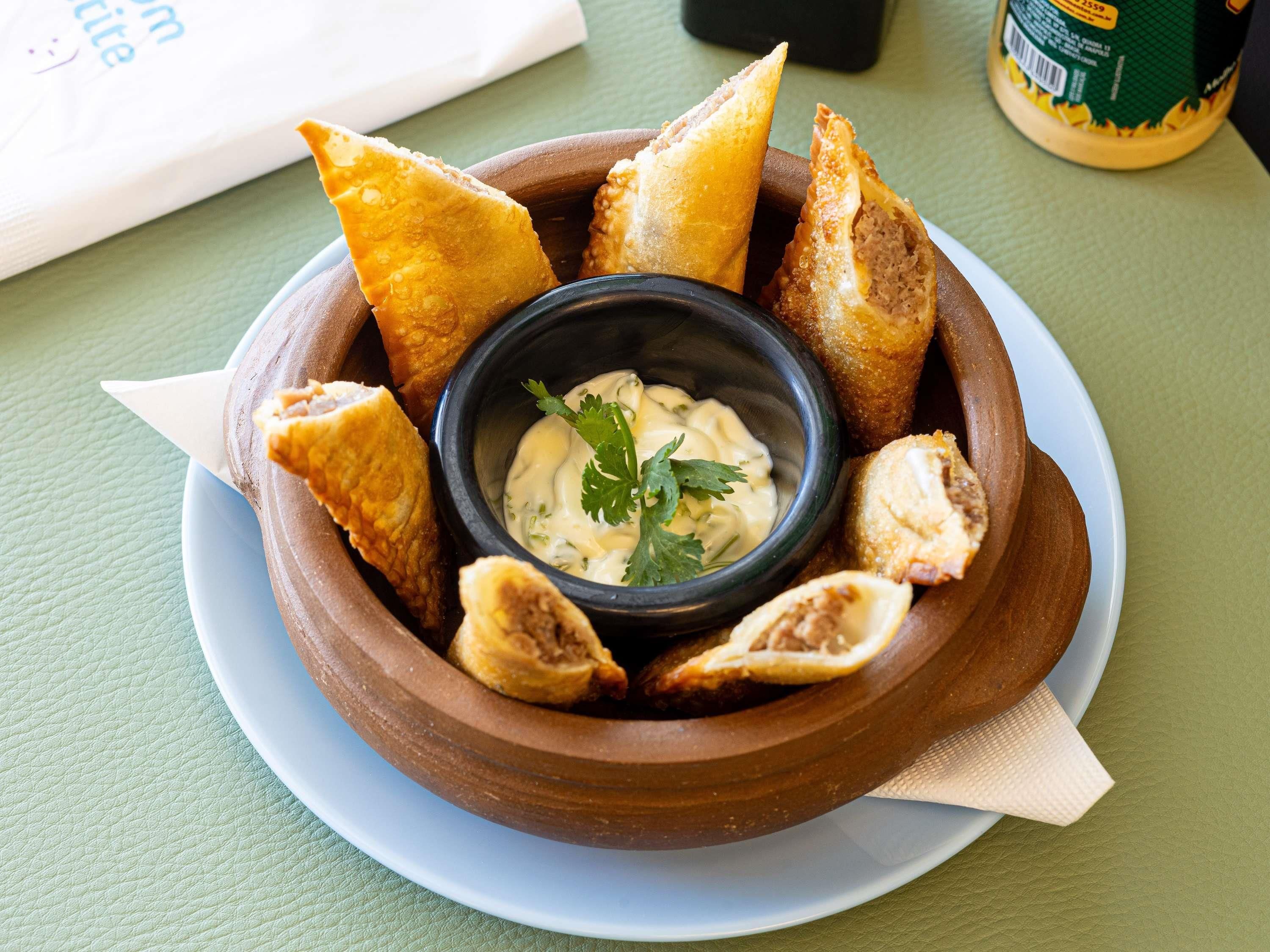 Een schaal eten met dipsaus en broodstengels op een bord.
