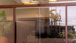 L'ingresso di ibis Styles con una porta in vetro, un cartello verde e lampade a sospensione.