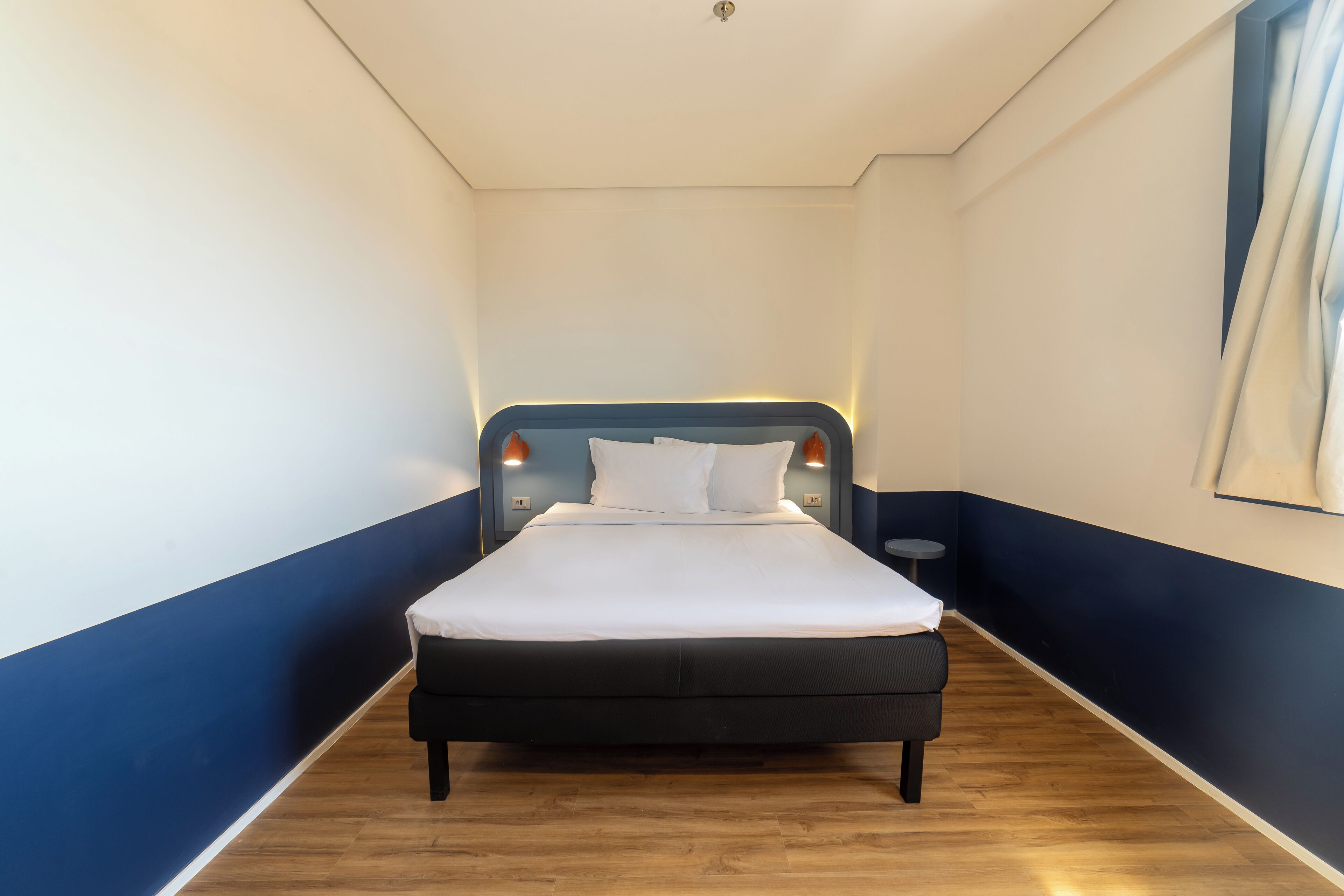 A bedroom with a bed, wooden floor, and blue and white walls.