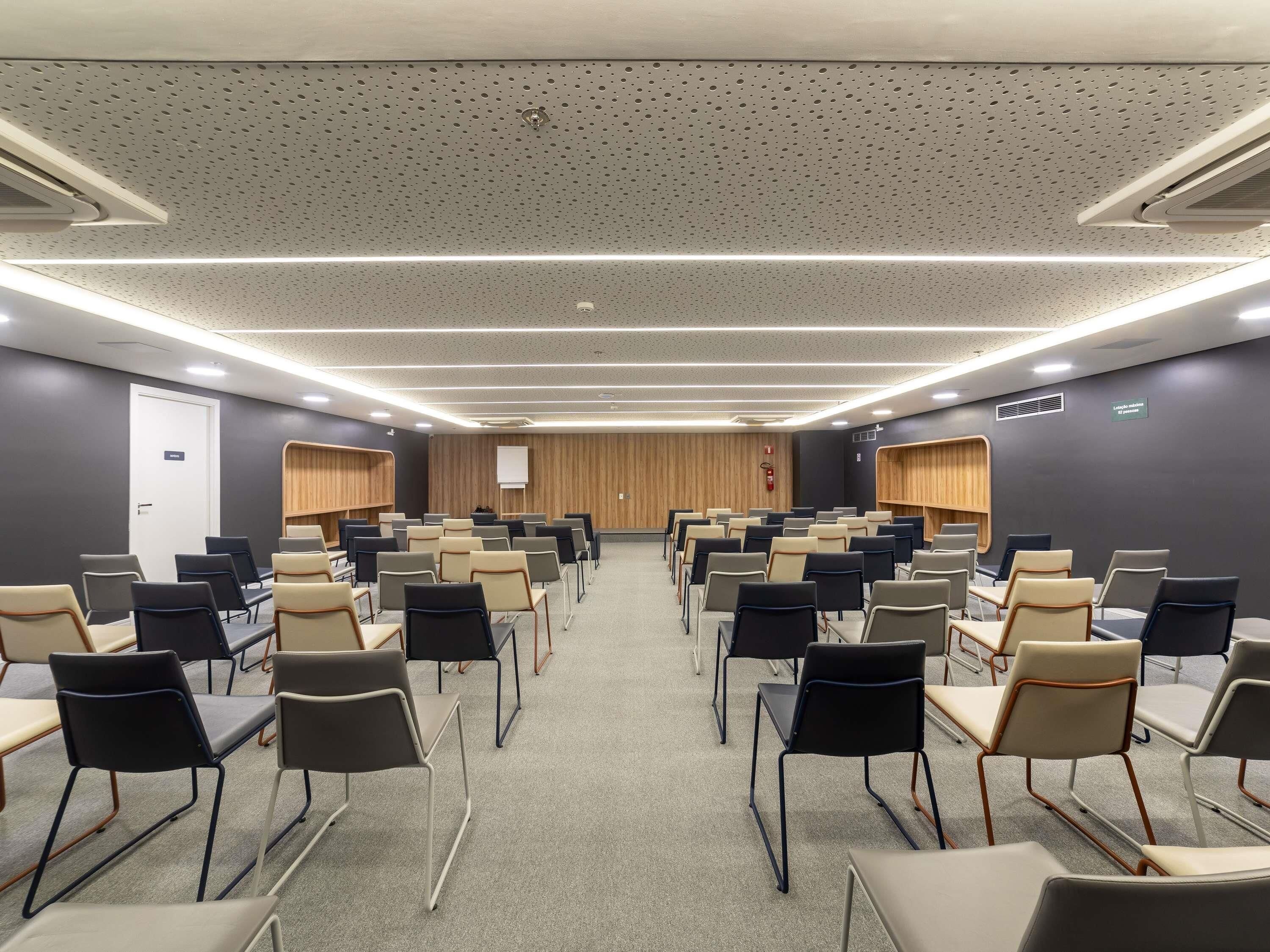A conference room with rows of chairs, a whiteboard, and wooden paneling on the walls.