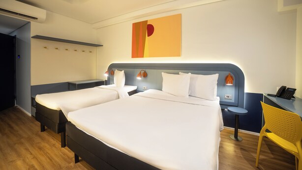 A hotel room with two beds, a desk, a chair, and a wall-mounted artwork. - Ibis Styles Fortaleza Giga Mall (Fortaleza)