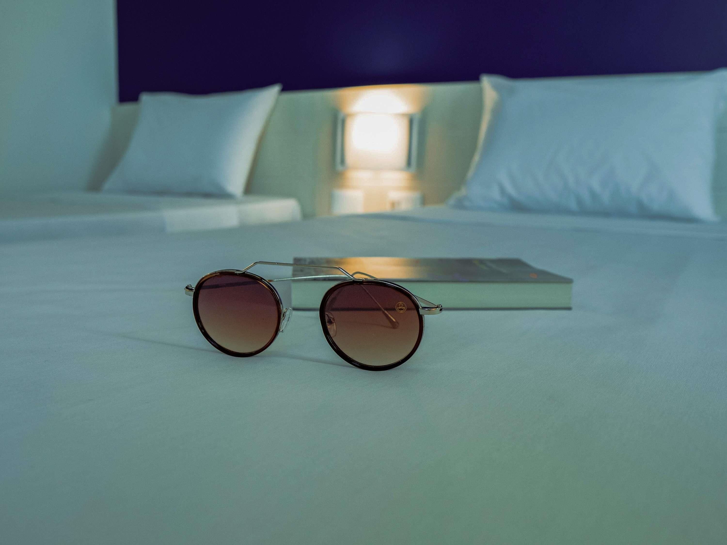 Una cama con un par de gafas de sol encima.