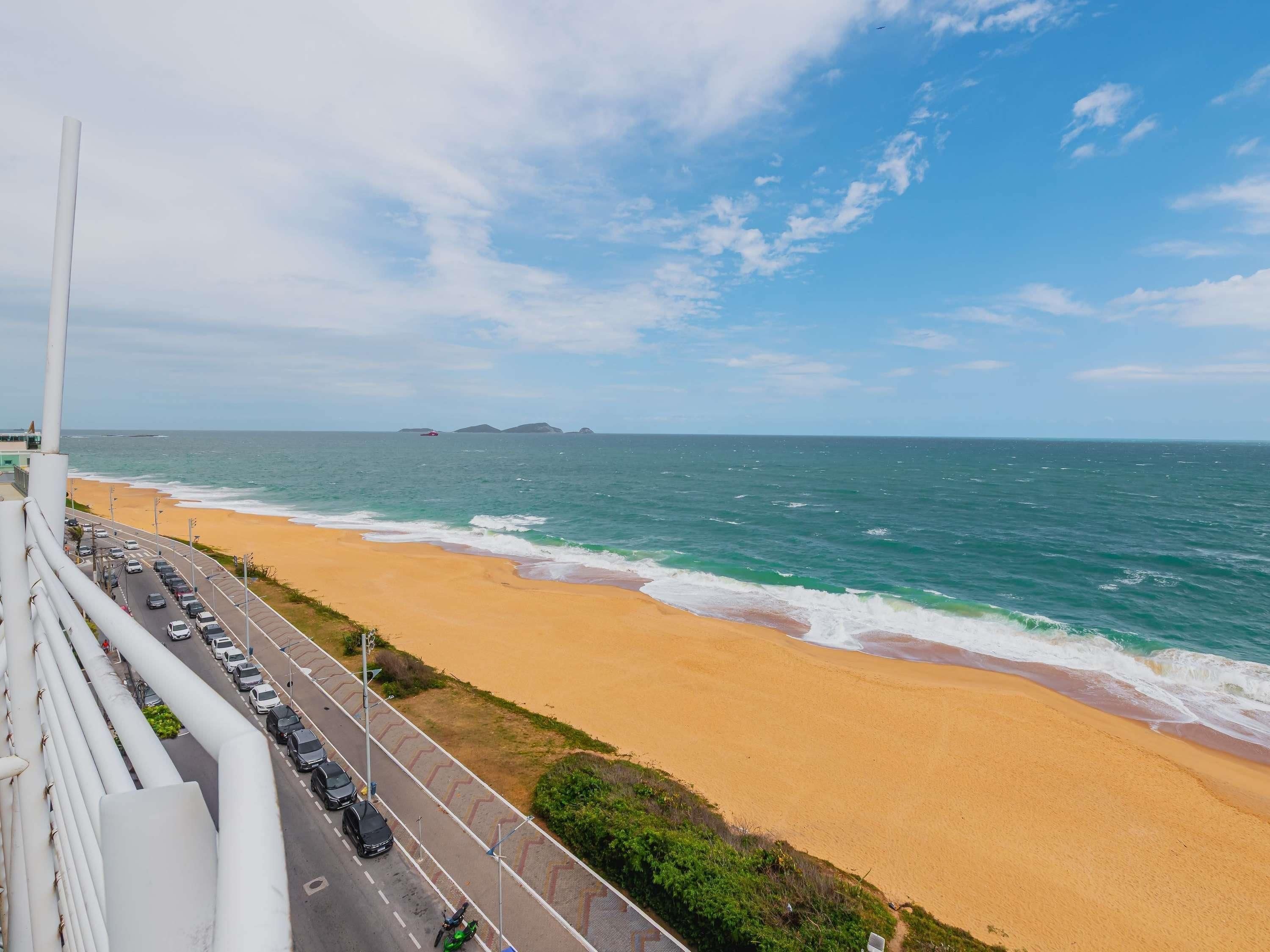 Uma estrada costeira com uma praia e o oceano ao fundo.