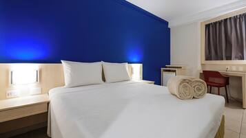 Quarto de hotel com uma cama grande, uma escrivaninha e uma cadeira.