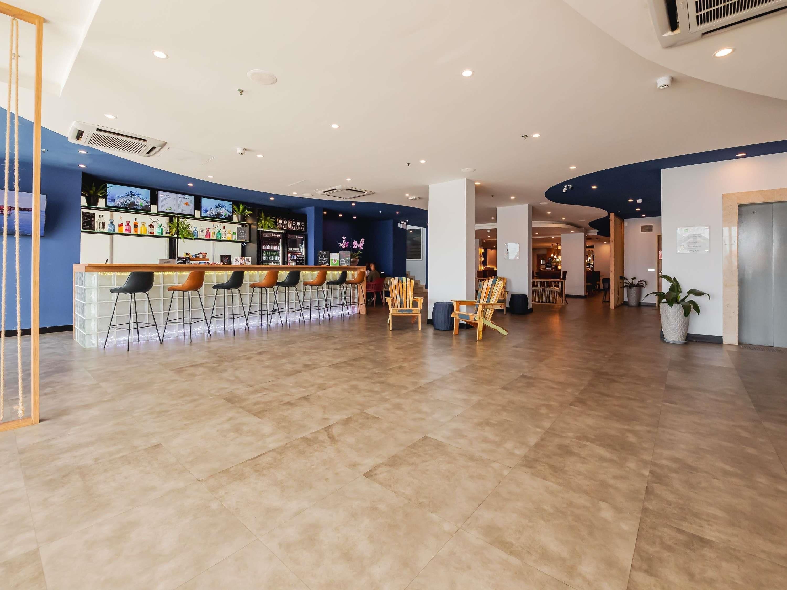 Zona de bar moderna con mostrador, taburetes y asientos.