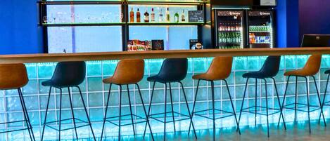 A bar area with a counter, multiple stools, and shelves with bottles.