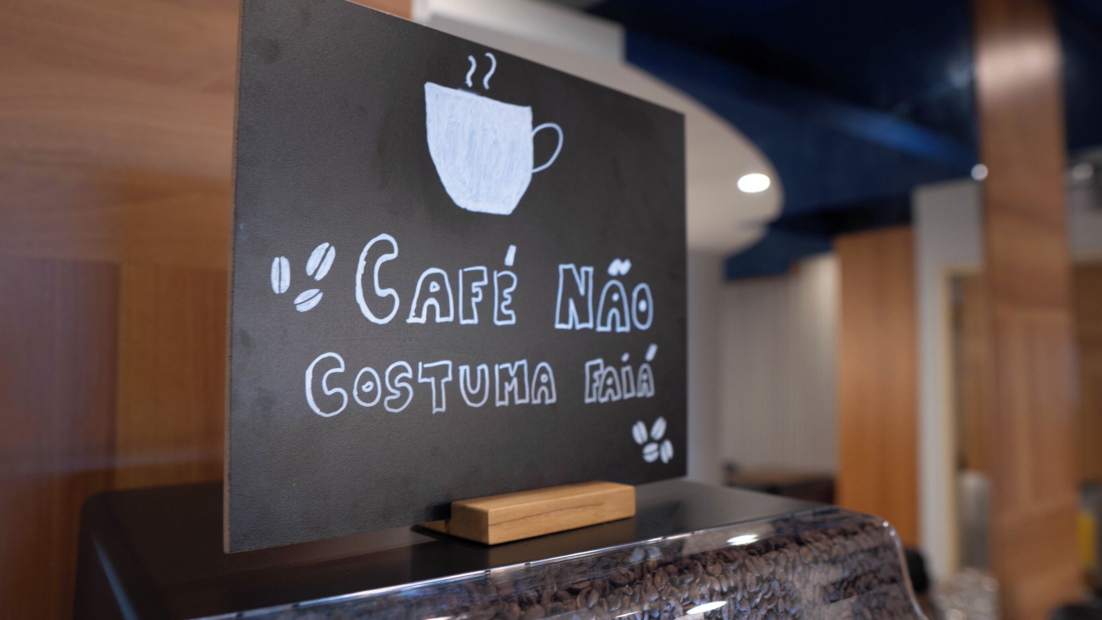 A sign with a coffee cup and text in a cafe setting.