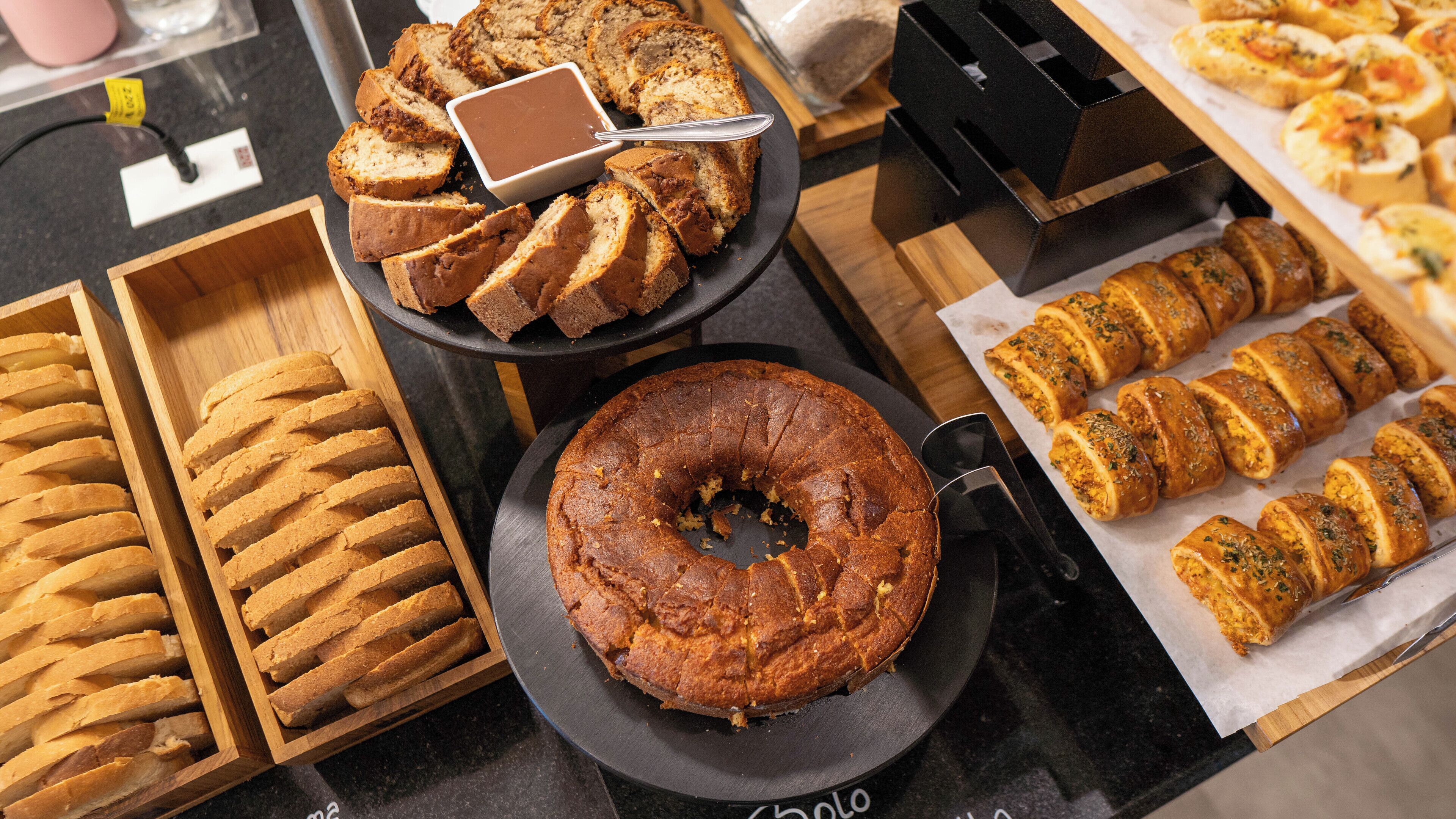 A variety of baked goods including bread, a bundt cake, and pastries on display.