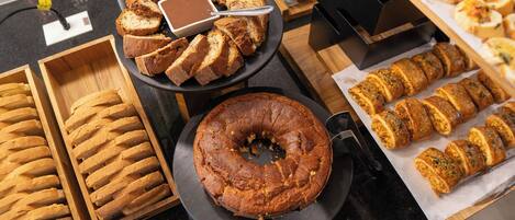 A variety of baked goods including bread, a bundt cake, and pastries on display.