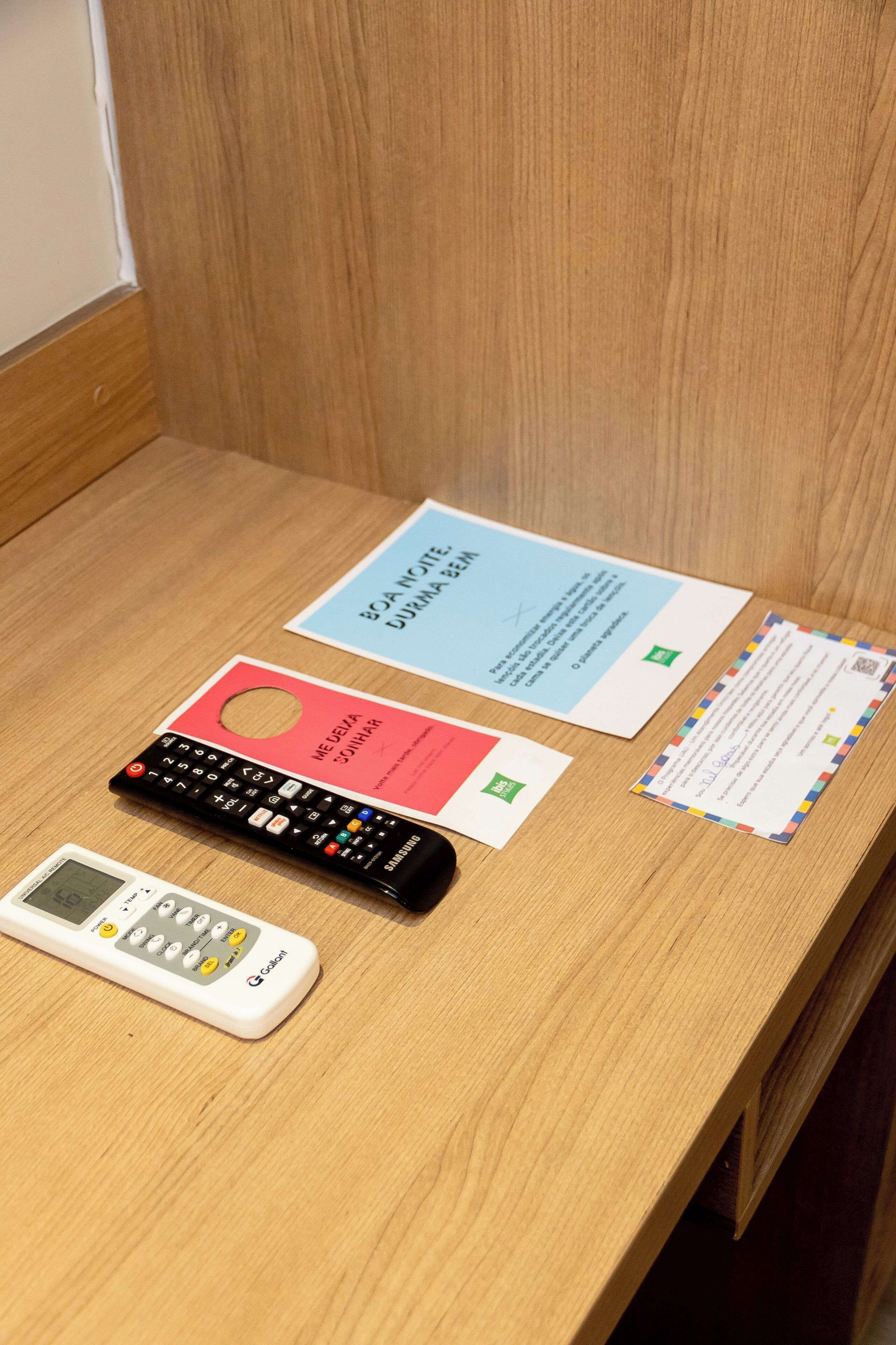 A wooden desk with a white digital scale, a black remote control, and three papers with text and symbols.