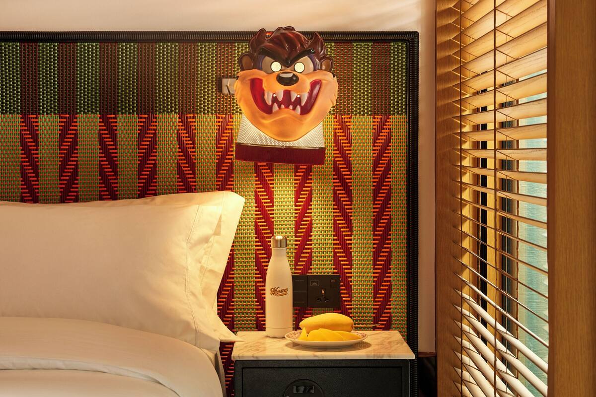 A hotel room with a bed, a nightstand with a lamp, and a wall decoration.