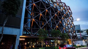 Un edificio moderno con fachada geométrica y una entrada bien iluminada.