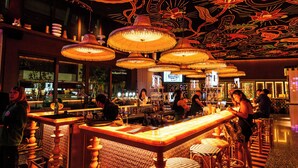 Un área de bar con suelo a cuadros, lámparas colgantes y un techo decorativo.