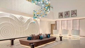 Um hall moderno com um sofá curvo, uma luminária pendente decorativa e um balcão de recepção.