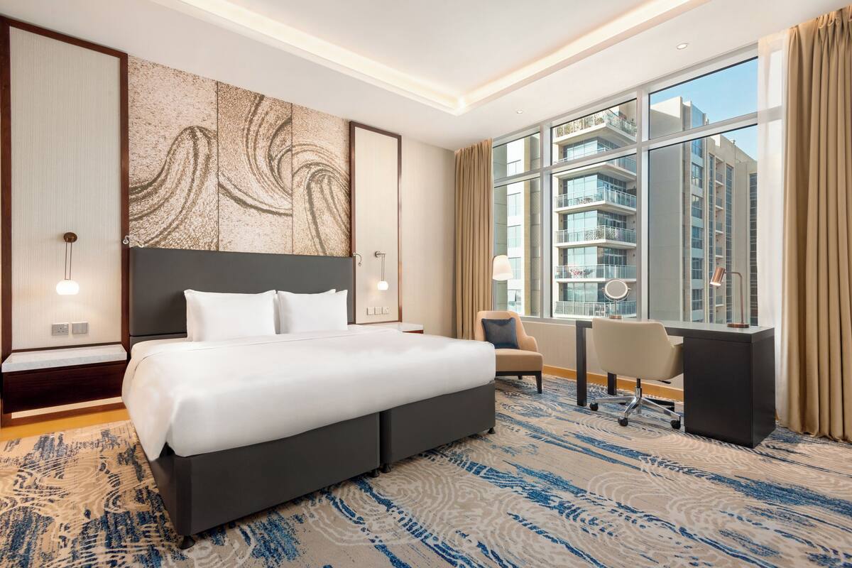 Une chambre d’hôtel moderne avec un grand lit, un bureau et une vue sur les gratte-ciel.