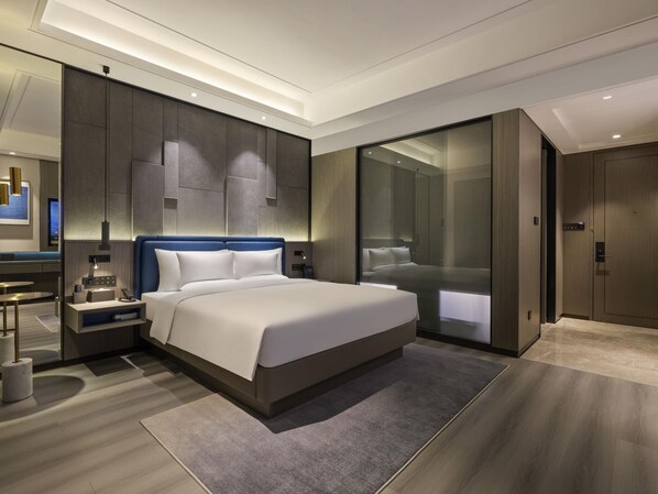 Ein modernes Hotelzimmer mit einem großen Bett, Nachttischen, einer eingebauten Garderobe und einem großen Spiegel.