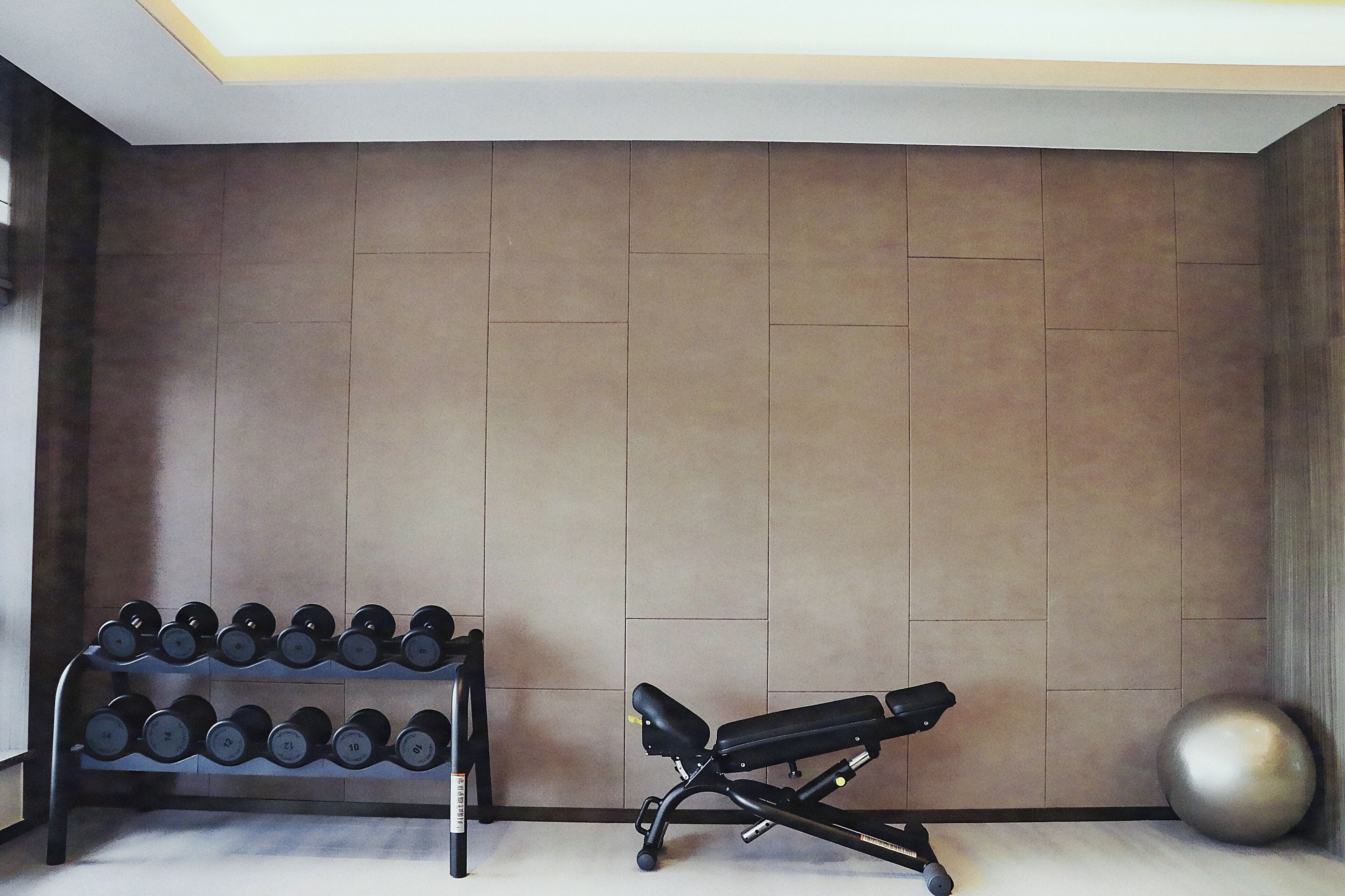 Een fitnessruimte met een bank, gewichten en een grote fitnessbal.