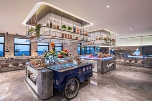 A modern buffet setup with tiered glass shelves displaying various food items and decorations.