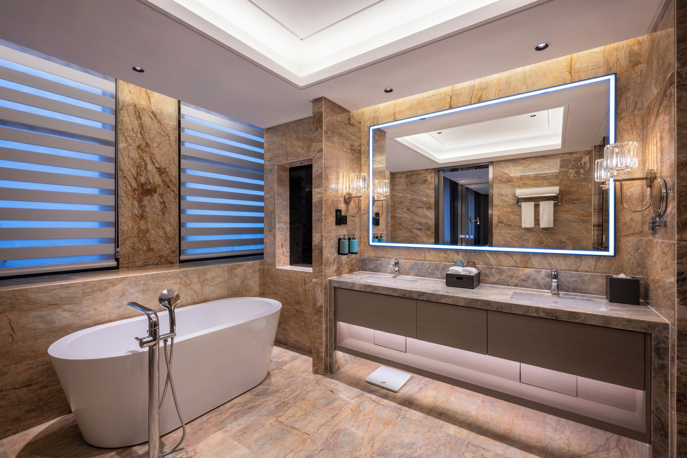 A modern bathroom with a freestanding bathtub, a large mirror, and a marble-tiled vanity.